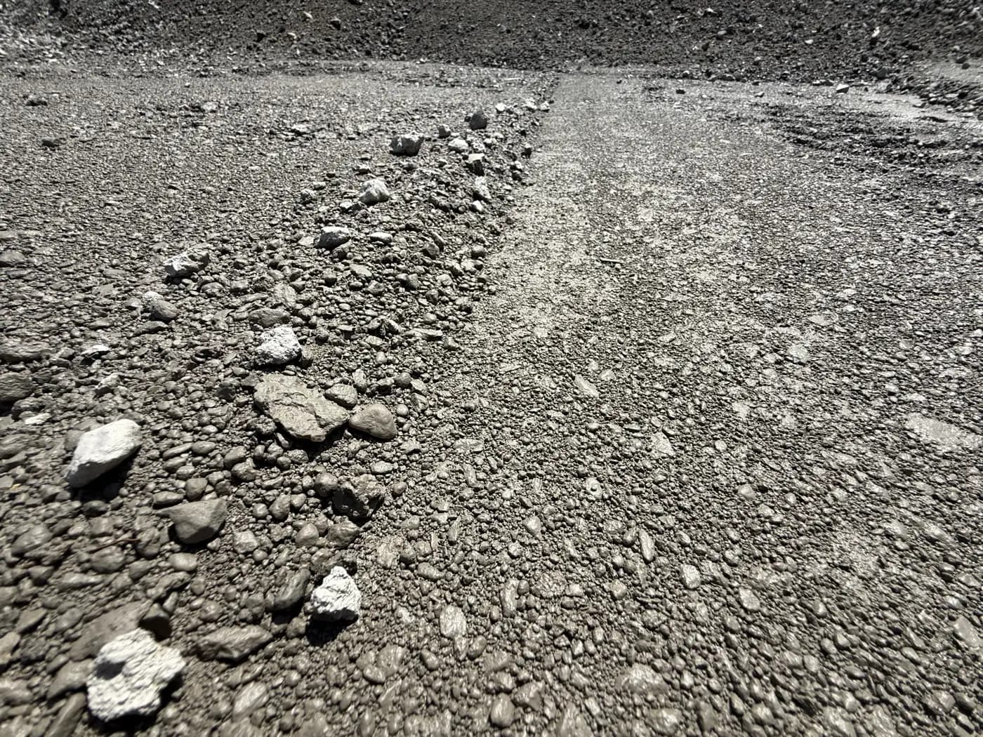 Freshly delivered 1½" dense grade gravel — compacted surface beside a raw pile after rain, showing the finished grade GravelRI delivers across Rhode Island
